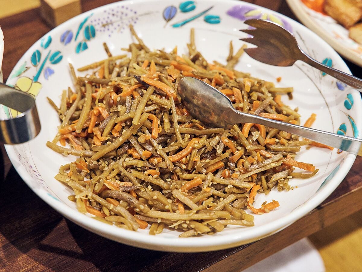 Un plato de vegetales salteados con cuchara y tenedor sobre una mesa.