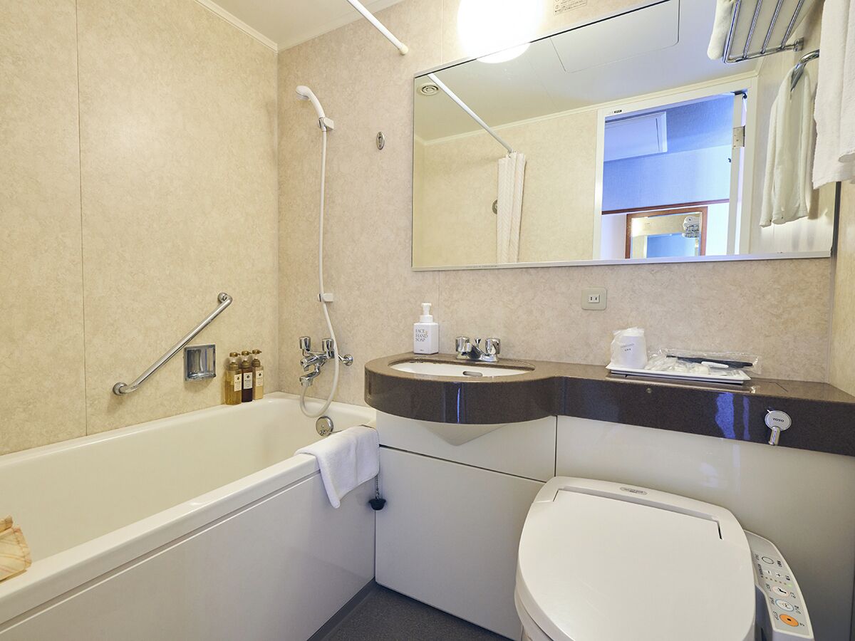 A bathroom with a bathtub, toilet, sink, and a mirror.