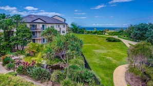 A residential building with a well-maintained lawn, a pathway, and a view of the ocean. - Currumbin Sands Holiday Apartments (Palm Beach)