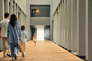 A corridor with a wooden floor and white walls, leading to a bright area at the end.
