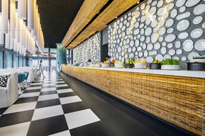 A modern restaurant with a checkered floor, a long counter with various dishes, and a wall decorated with plates.