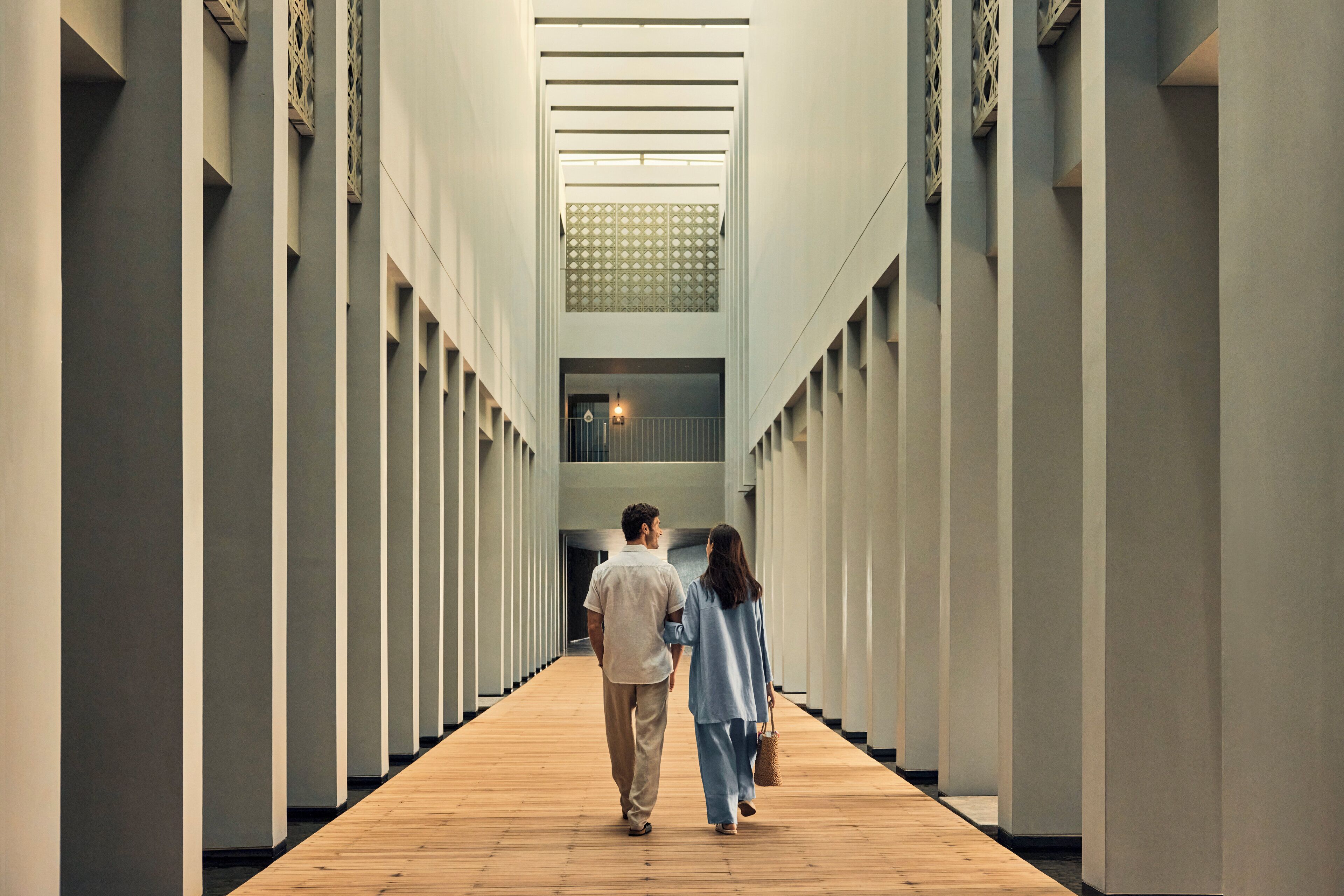 A corridor with a wooden floor and white walls, leading to a staircase.
