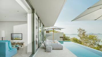 Un espacio exterior moderno con piscina, mobiliario y vista al mar.