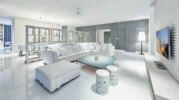Een moderne woonkamer met een modulaire bank, een glazen salontafel en witte decoratieve objecten.
