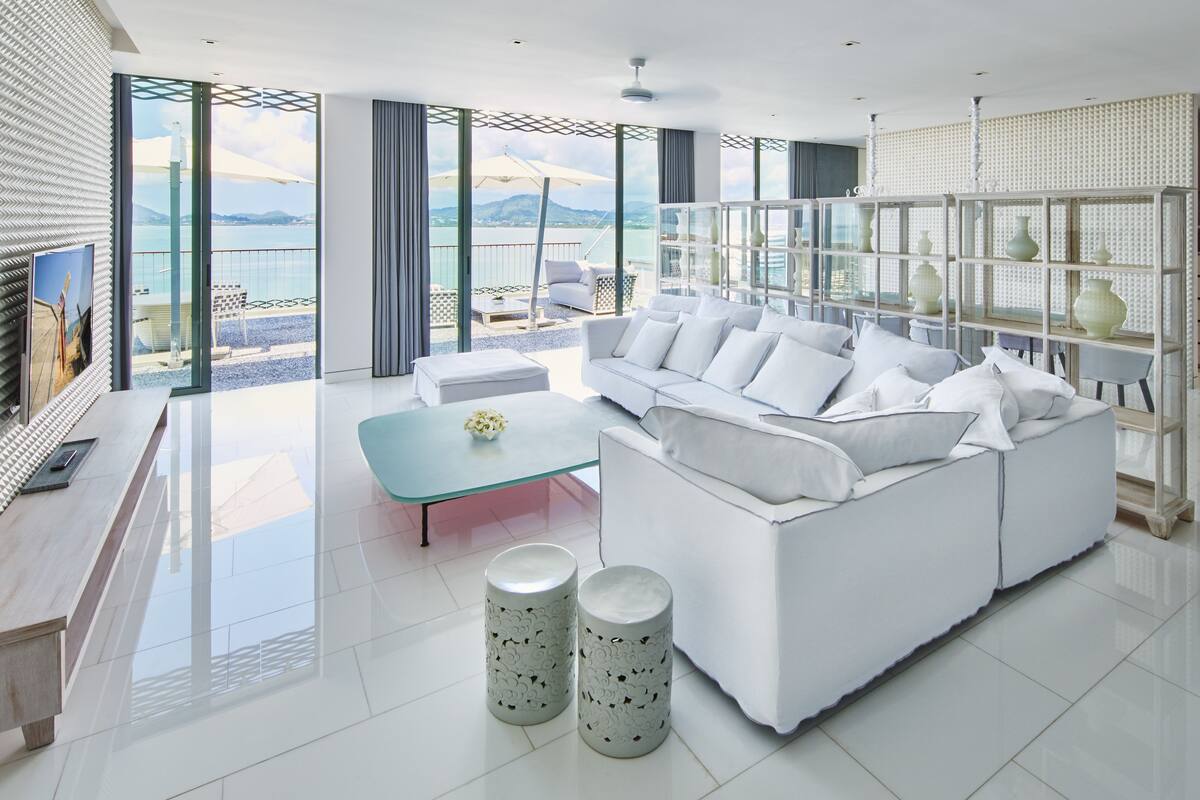 Een moderne woonkamer met een witte bank, een glazen salontafel en decoratieve vazen.