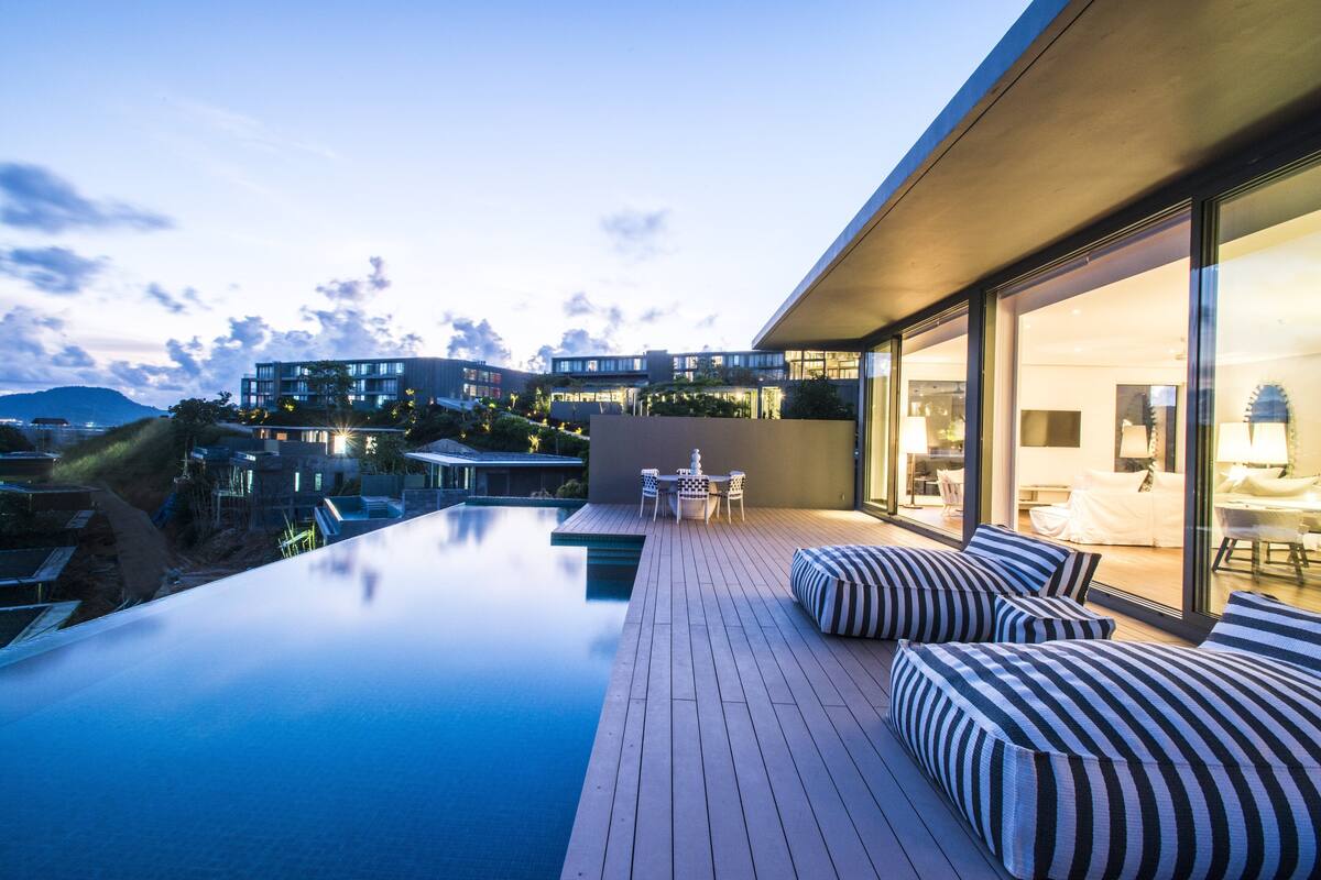 Een modern dakzwembad met een houten terras, comfortabele zitplaatsen en uitzicht op de omliggende gebouwen.