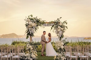 A wedding ceremony with a floral arch and chairs arranged for guests.