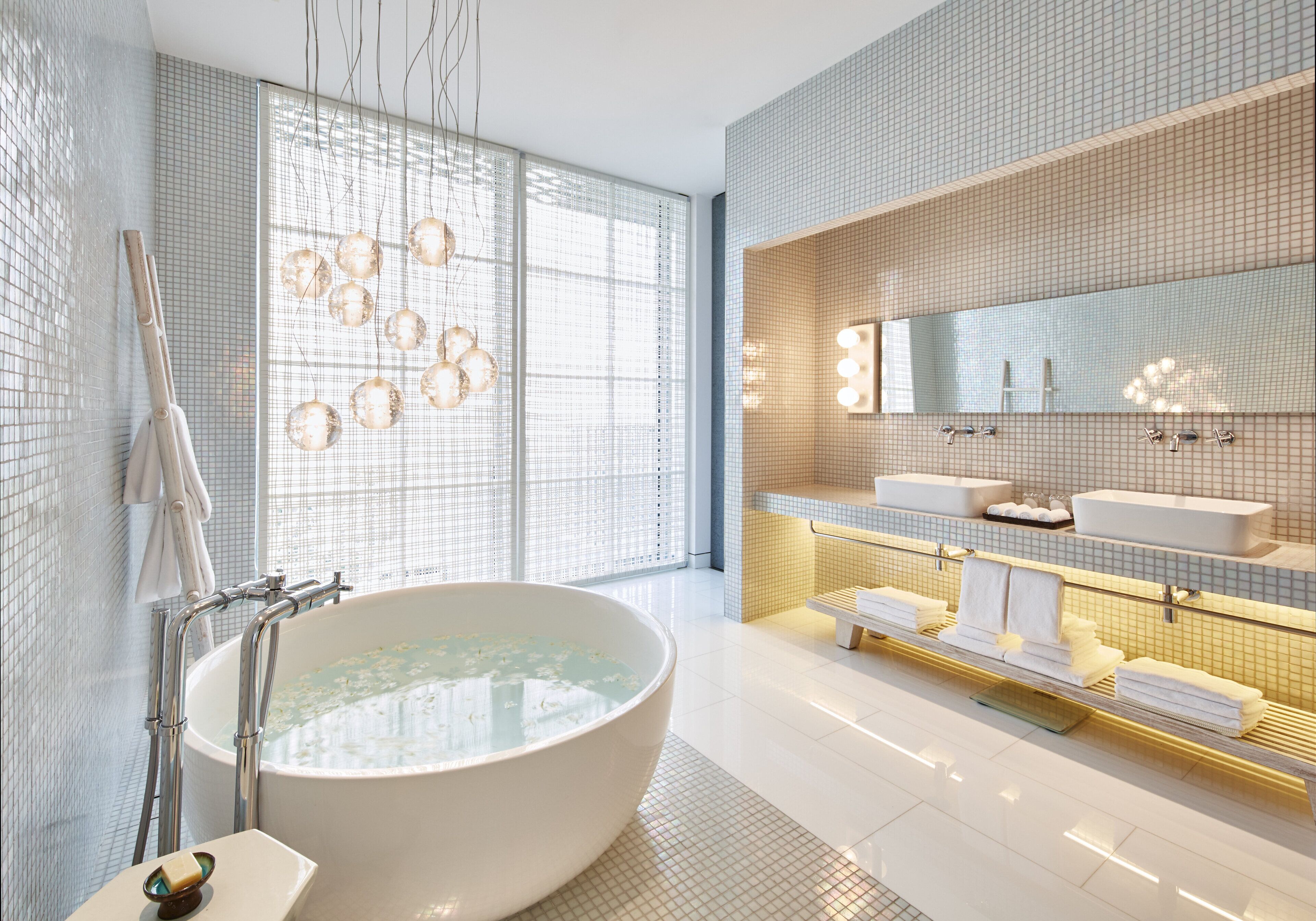 A modern bathroom with a large freestanding bathtub, a vanity with a mirror, and a towel rack.