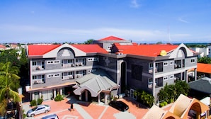 A multi-story building with a red roof, large windows, and a central courtyard. - MJ Grand Hotel (Accra)