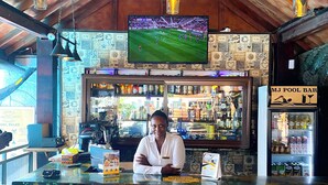 A bar area with a bartender, a television screen, and a pool bar sign. - MJ Grand Hotel (Accra)