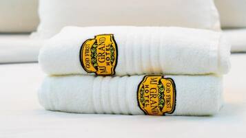 Dos toallas blancas dobladas con etiquetas bordadas que dicen 'God First MI GRAND HOTEL'.