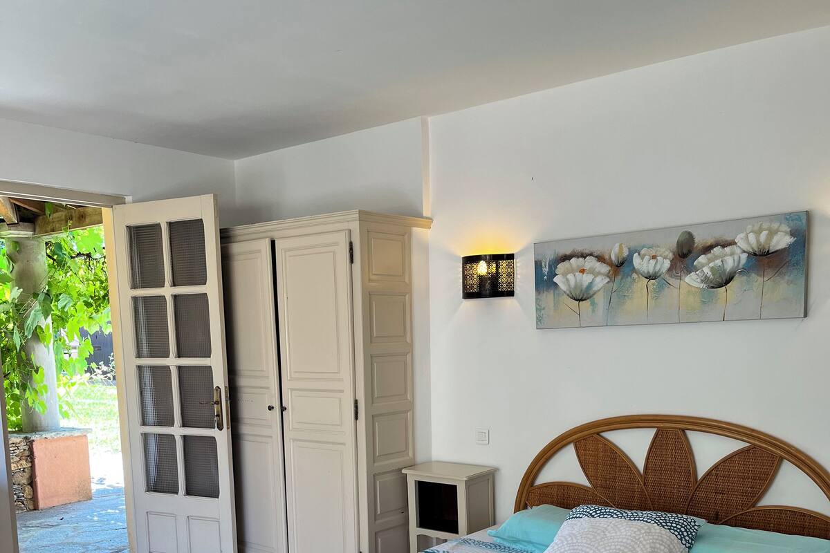 A bedroom with a bed, a nightstand, a wardrobe, and a painting on the wall.