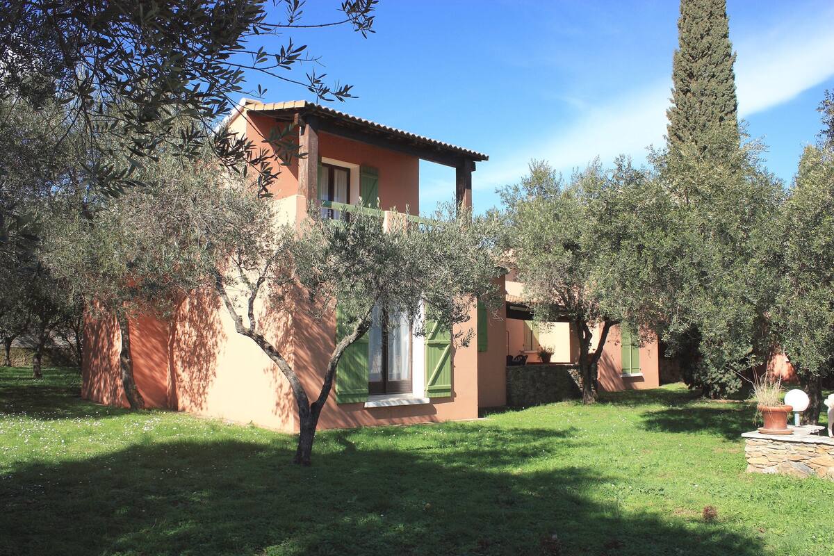 A rustic villa with a tiled roof, surrounded by olive trees and a well-maintained lawn.