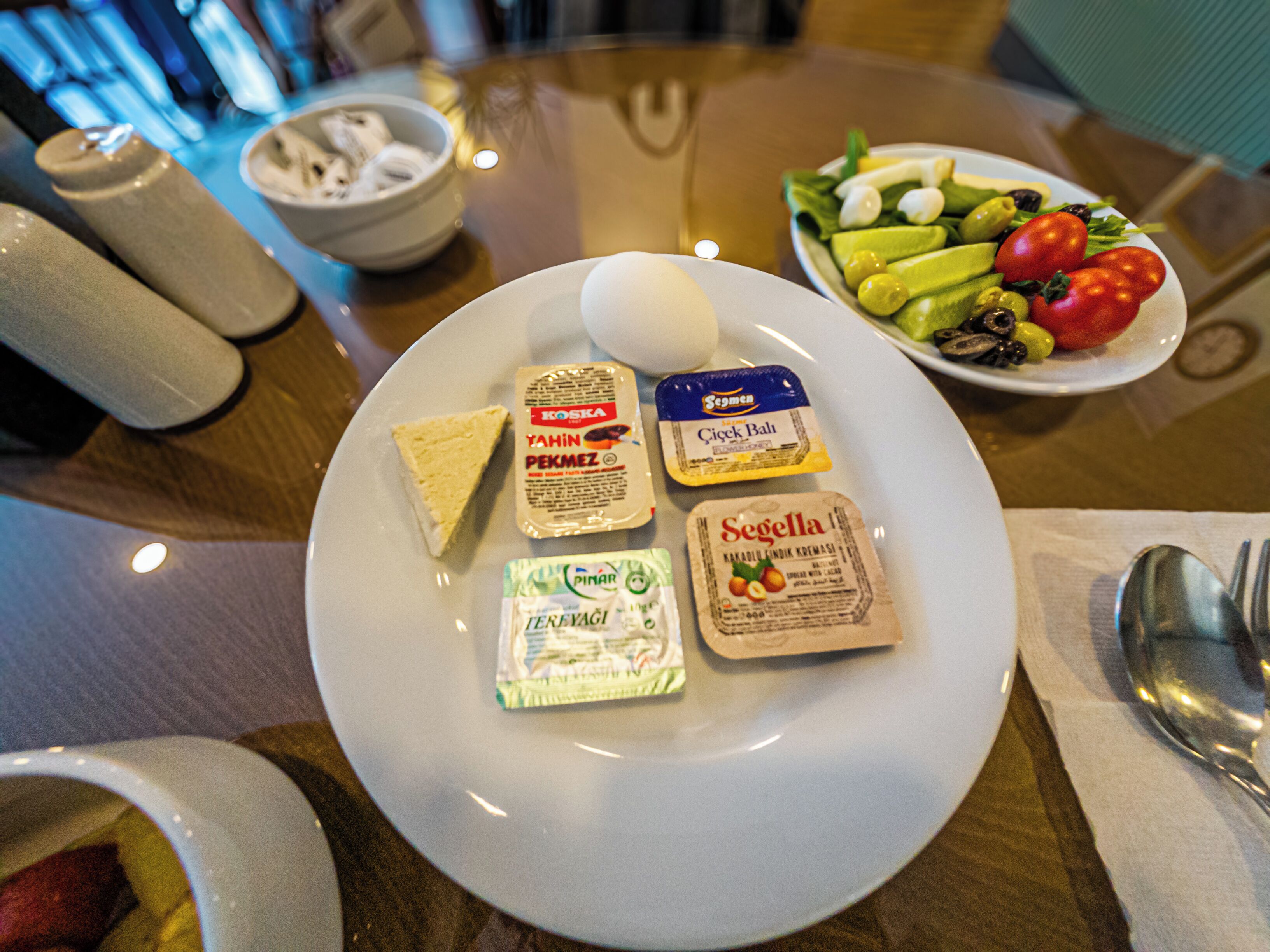 A dining table with a plate of food, including a salad, cheese, and yogurt.