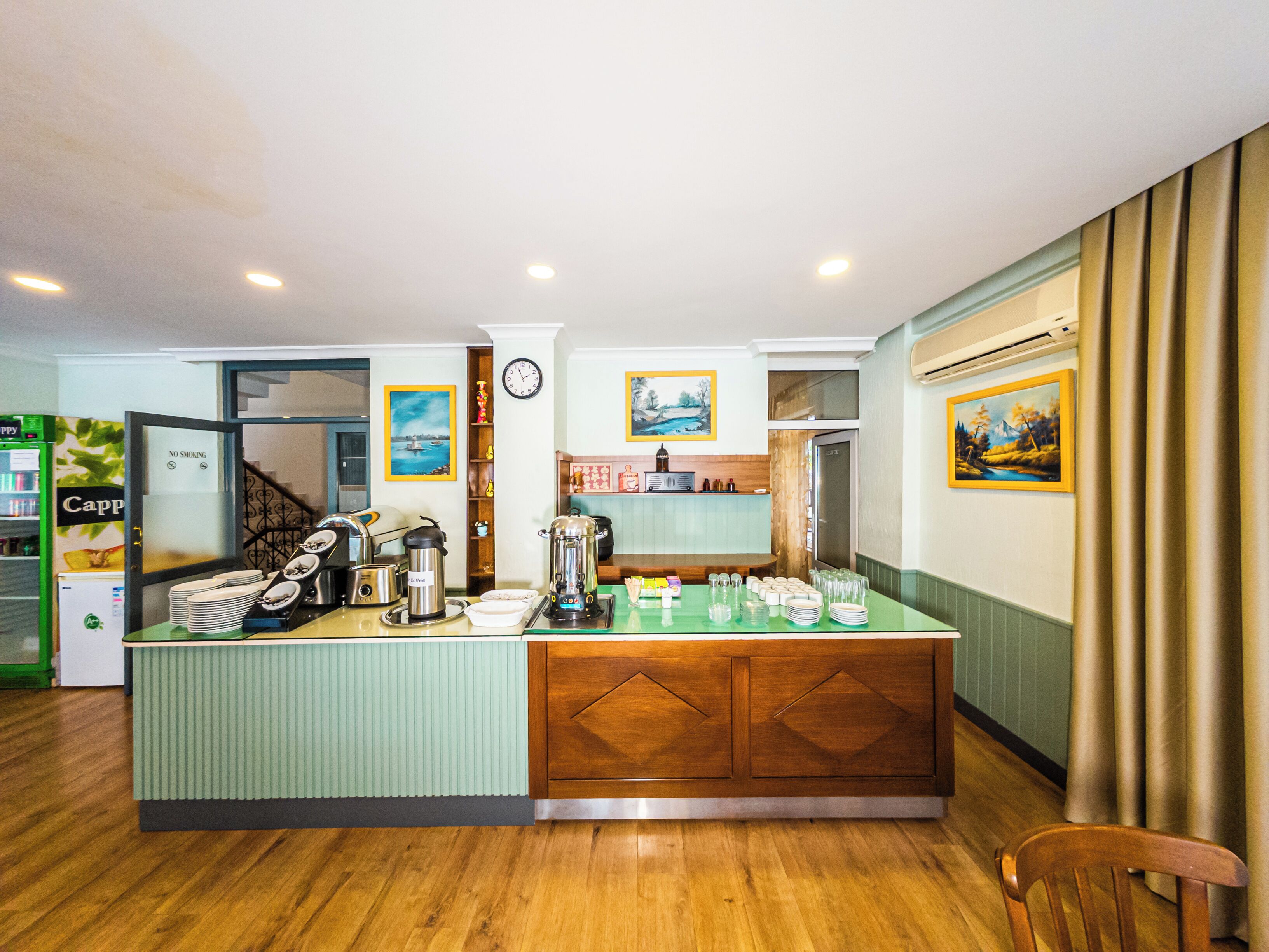 A hotel lobby with a reception desk, a clock, and a coffee machine.
