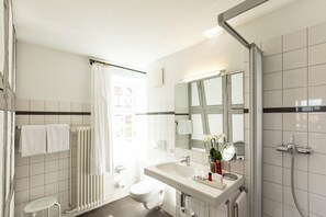 A modern bathroom with a toilet, sink, shower, and a large mirror. - Hotel de charme Römerhof (Arbon)