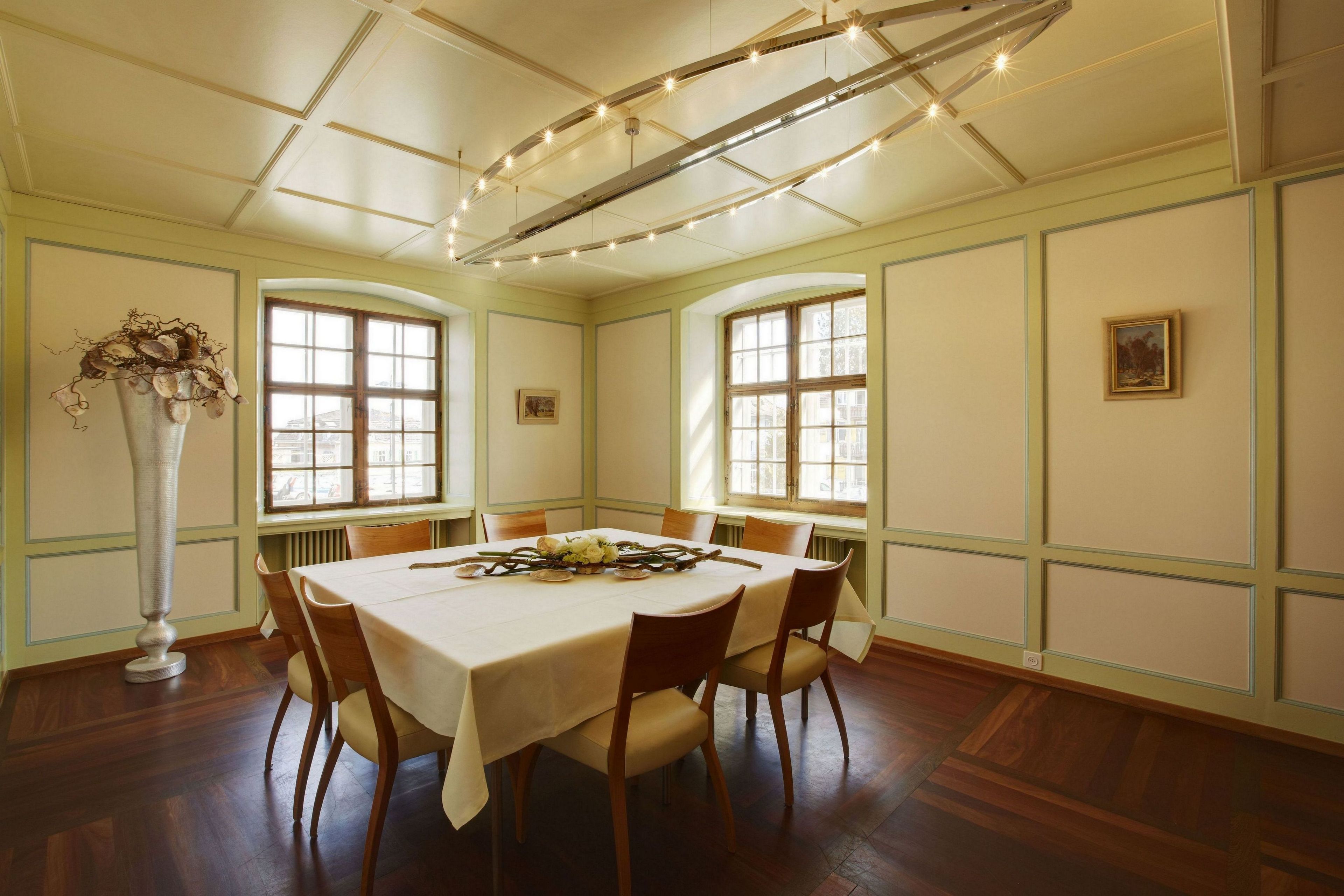 Une salle à manger avec une table ronde, des chaises, un vase et un lustre.