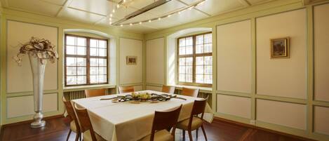 Une salle à manger avec une table ronde, des chaises, un vase et un lustre.