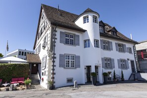 A white building with grey shutters, a curved tower, and a staircase leading to the entrance. - Hotel de charme Römerhof (Arbon)