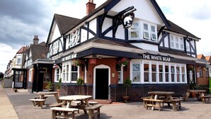 Un pub tradicional llamado "The White Bear", con mesas al aire libre y una fachada clásica en blanco y negro.
