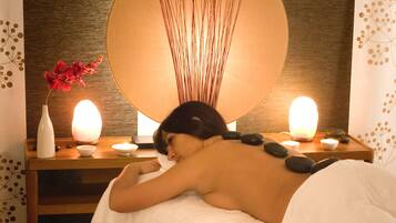Experience a rejuvenating massage in a serene spa setting with a large mirror, massage table, and soothing ambiance.