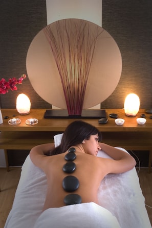 A person receiving a back massage with heated stones.