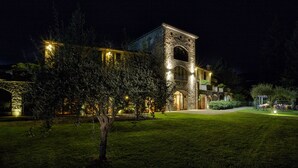 A stone building with a tower at night, surrounded by a well-maintained lawn and trees. - Cà del Moro Resort (Pontremoli)