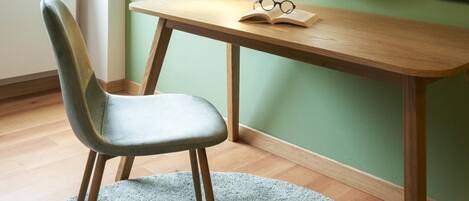 A study room with a desk, chair, round mirror, and a lamp.