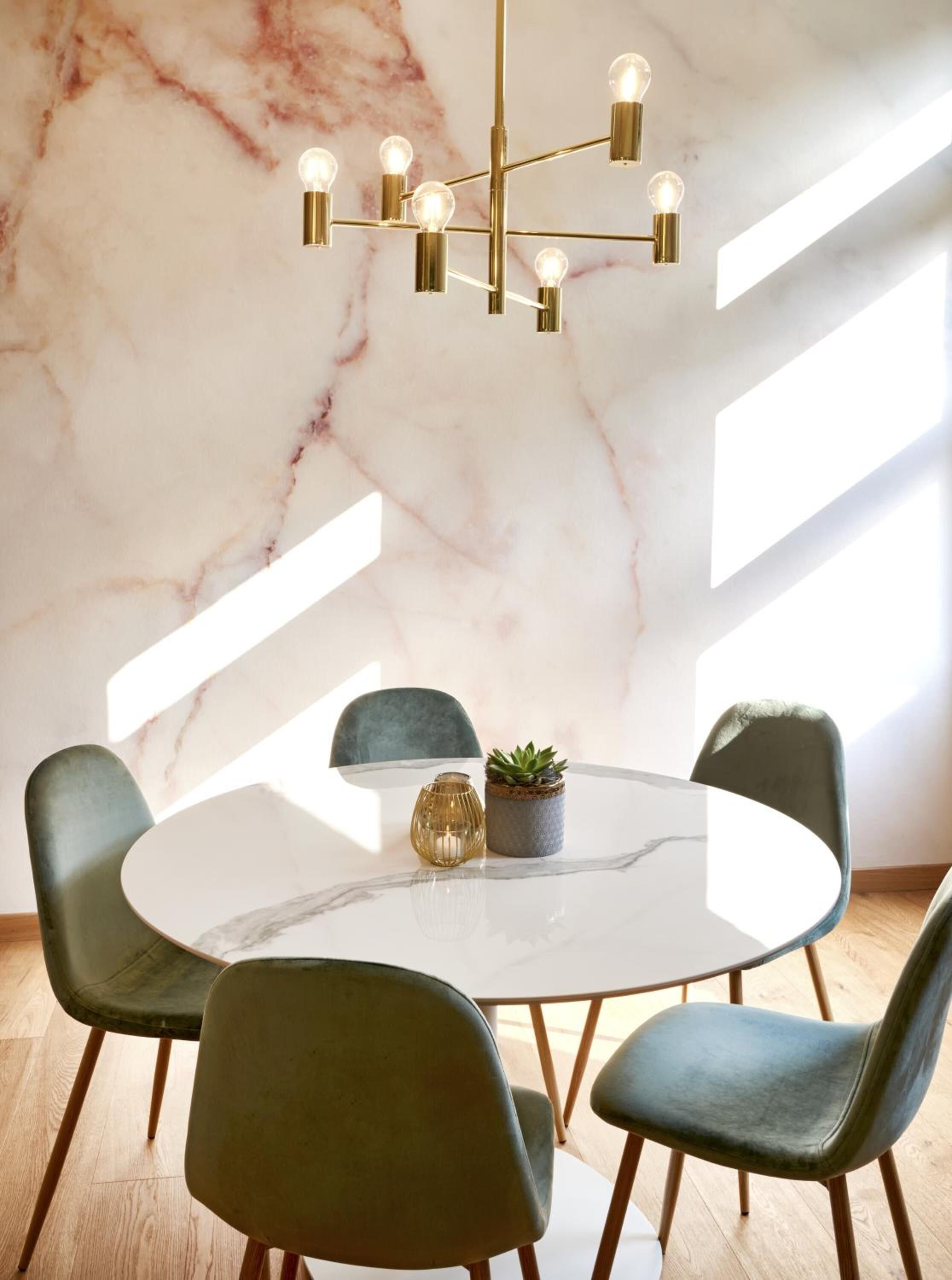 Un comedor con pared de mármol, una mesa redonda y cuatro sillas.