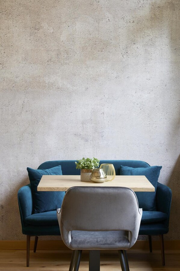 A room with a blue sofa, a wooden table, and a grey chair.