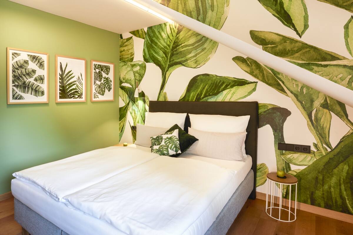 Une chambre à coucher avec un lit, des murs verts et une grande plante.