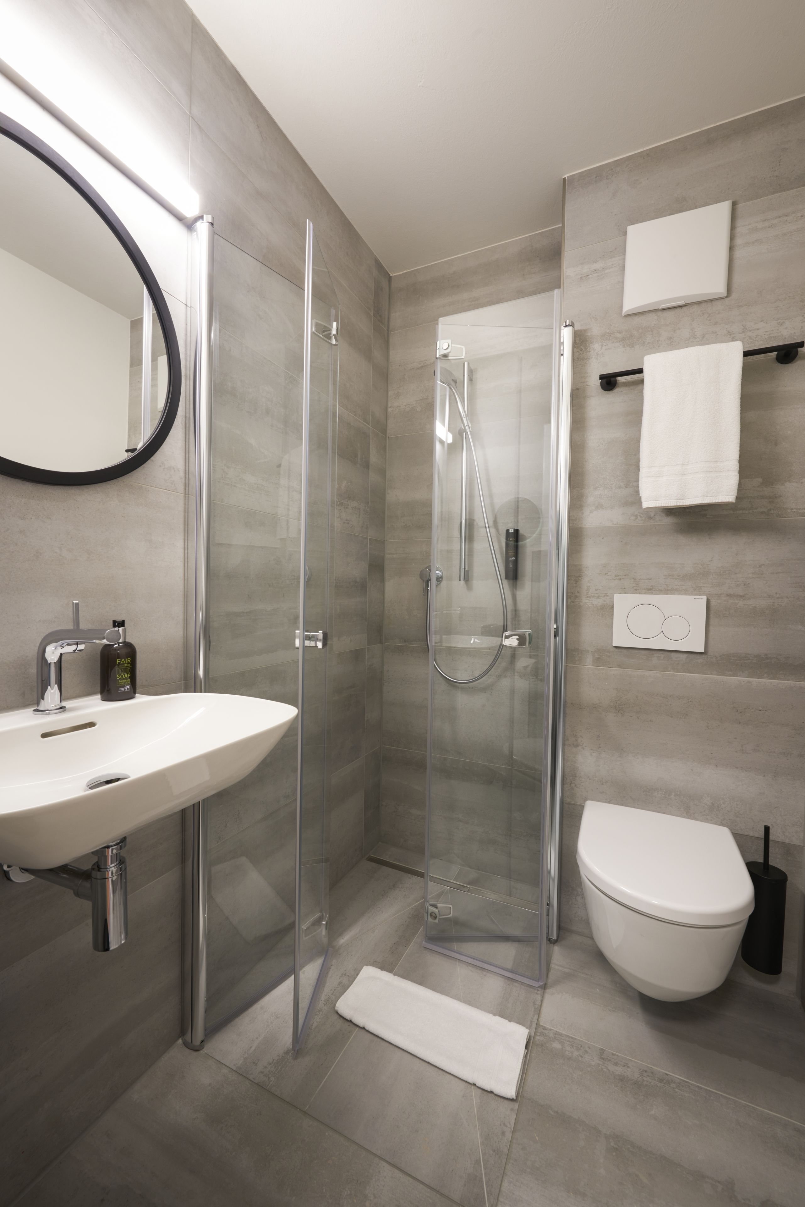 Un baño moderno con ducha de vidrio, lavamanos blanco y retrete.