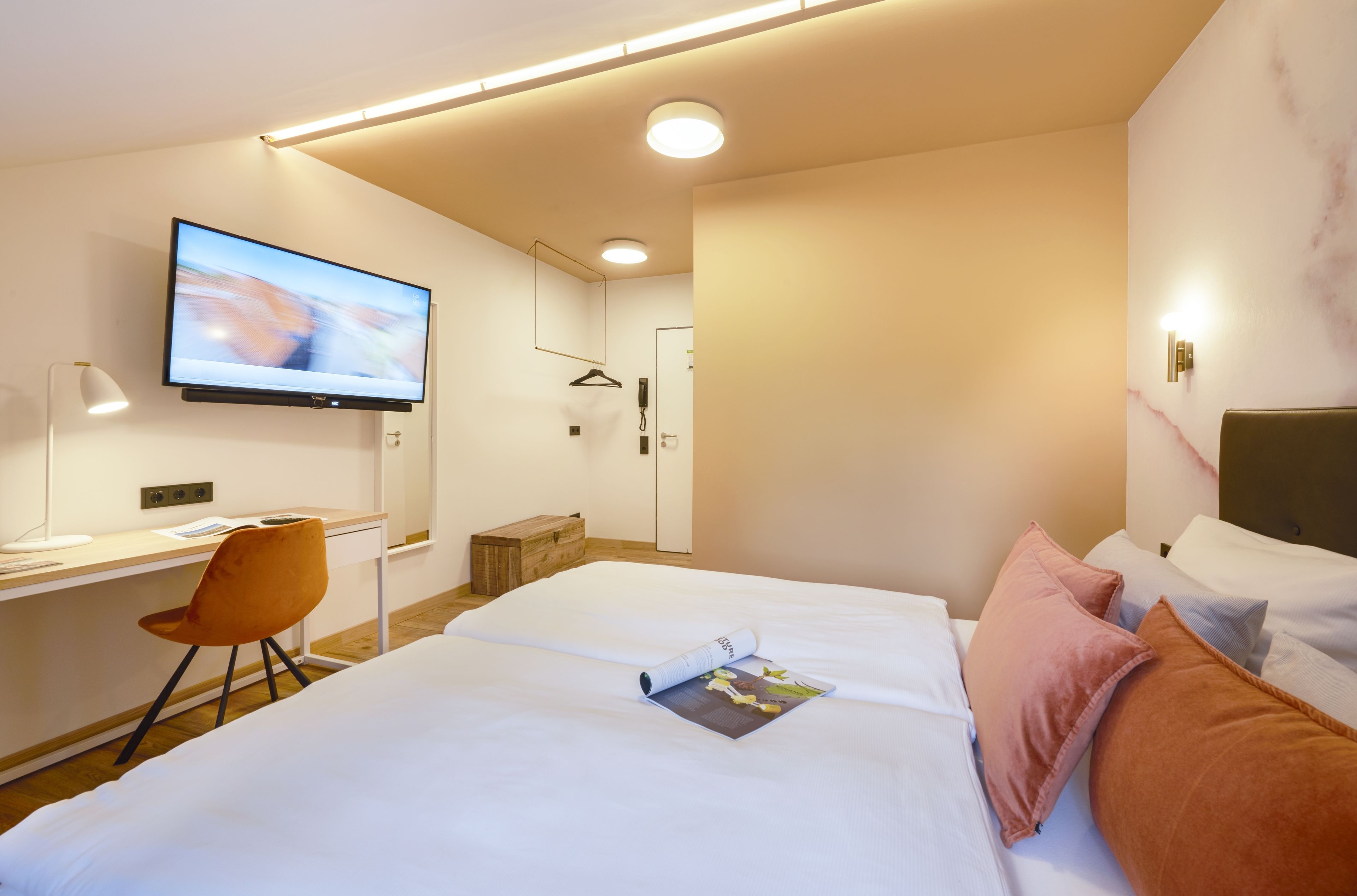 Una habitación de hotel moderna con una cama grande, un escritorio con silla, un televisor y la puerta del baño.