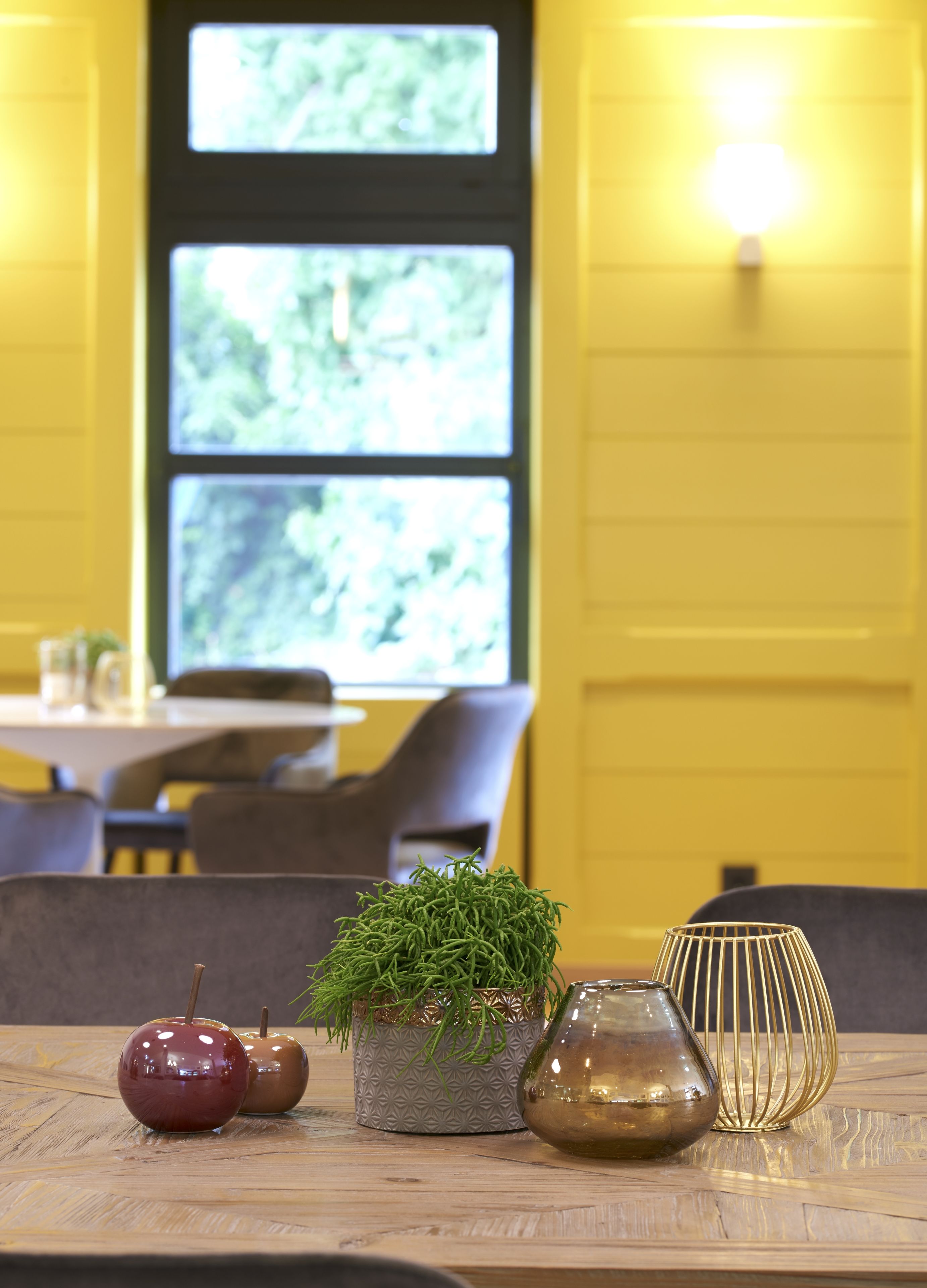 Una mesa con dos manzanas, una planta en maceta y una jarra de cristal en un restaurante.