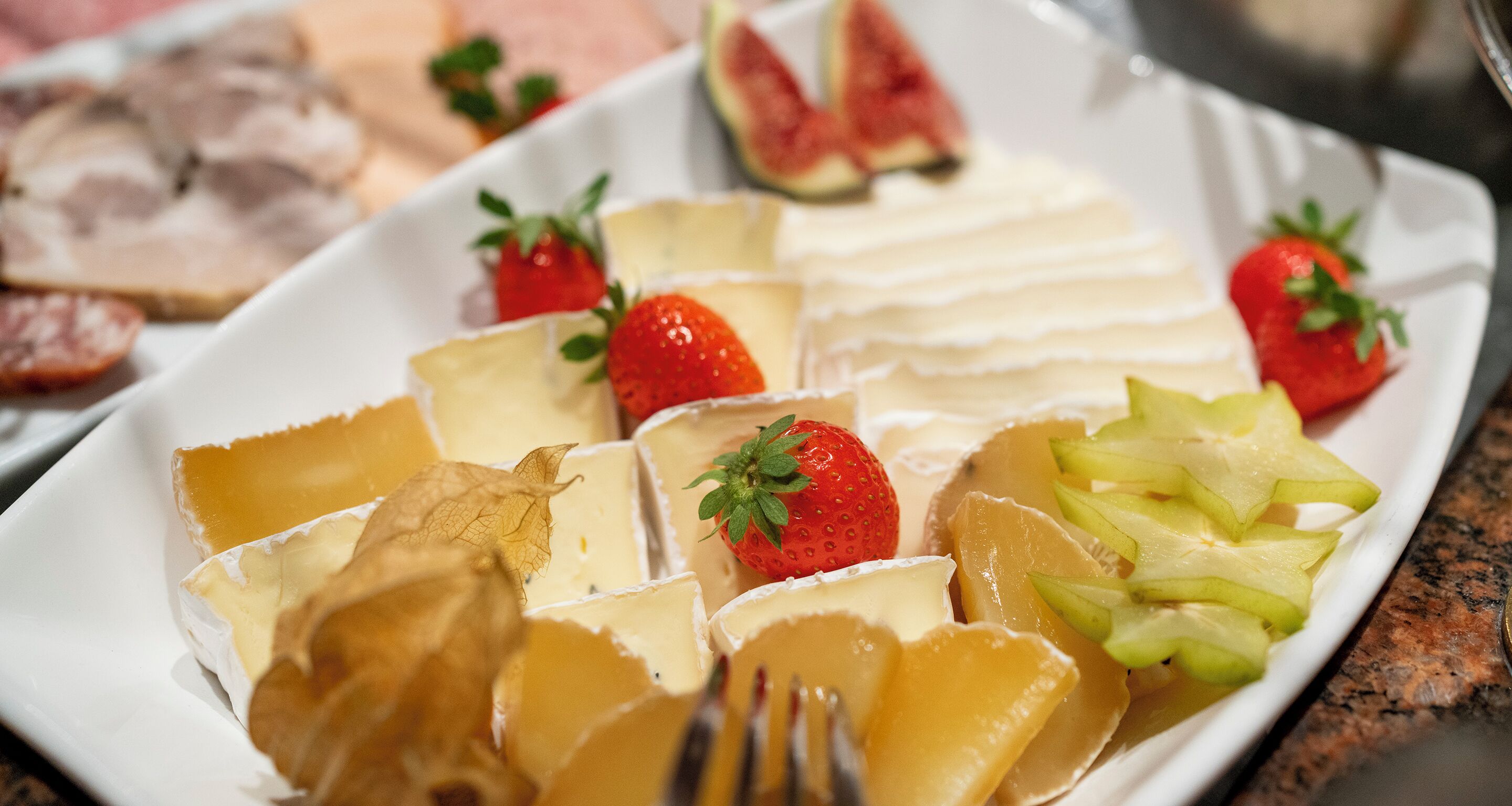 A plate with various cheeses and fruits, including strawberries and pineapple.