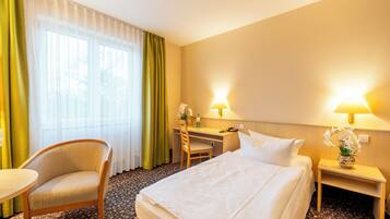 Ein Hotelzimmer mit Bett, Schreibtisch, Stuhl und kleinem Tisch.