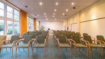 Ein Konferenzraum mit Reihen von Stühlen, großen Fenstern und einem Teppichboden.