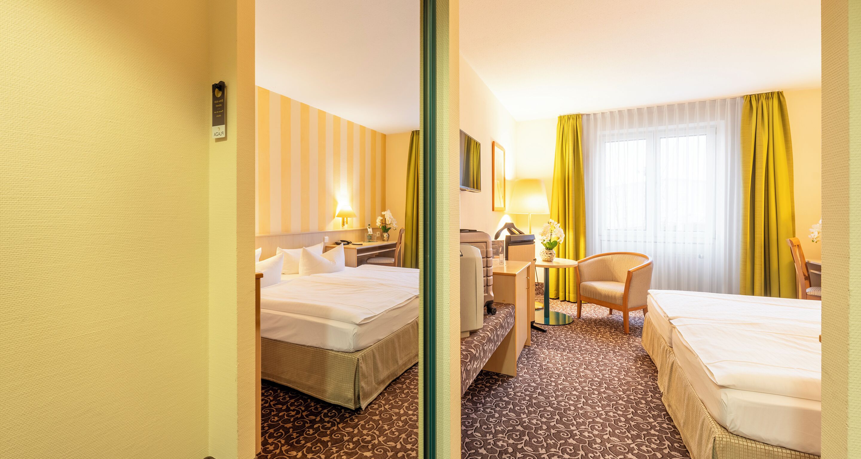 A hotel room with two beds, a desk, a chair, and a window with curtains.