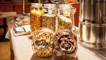 A breakfast buffet with various food items in jars and a coffee machine.