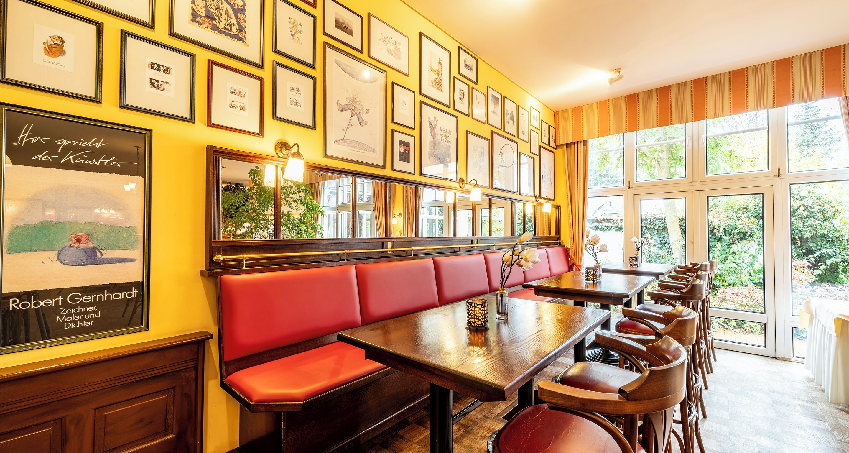 A restaurant with red cushioned booths, wooden tables, and framed artwork on the walls.