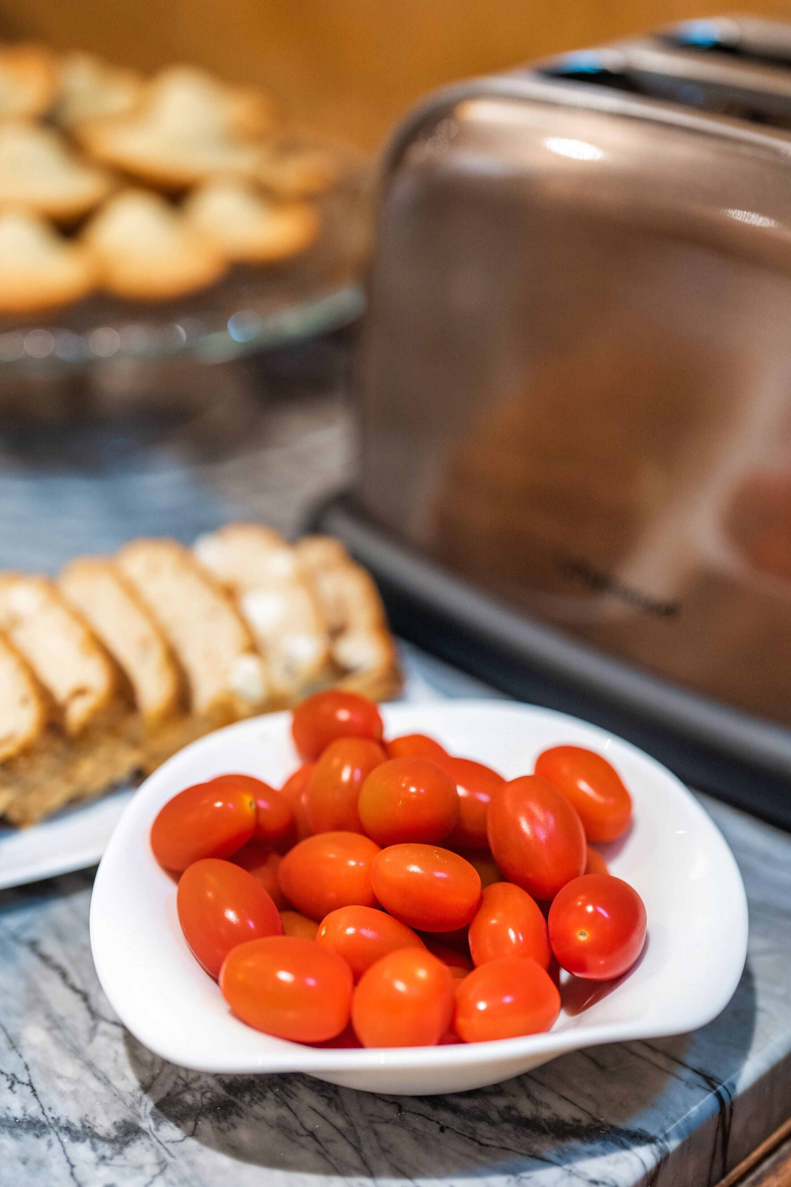 Um prato branco com tomates cereja em uma bancada de mármore.