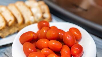 Um prato branco com tomates cereja em uma bancada de mármore.
