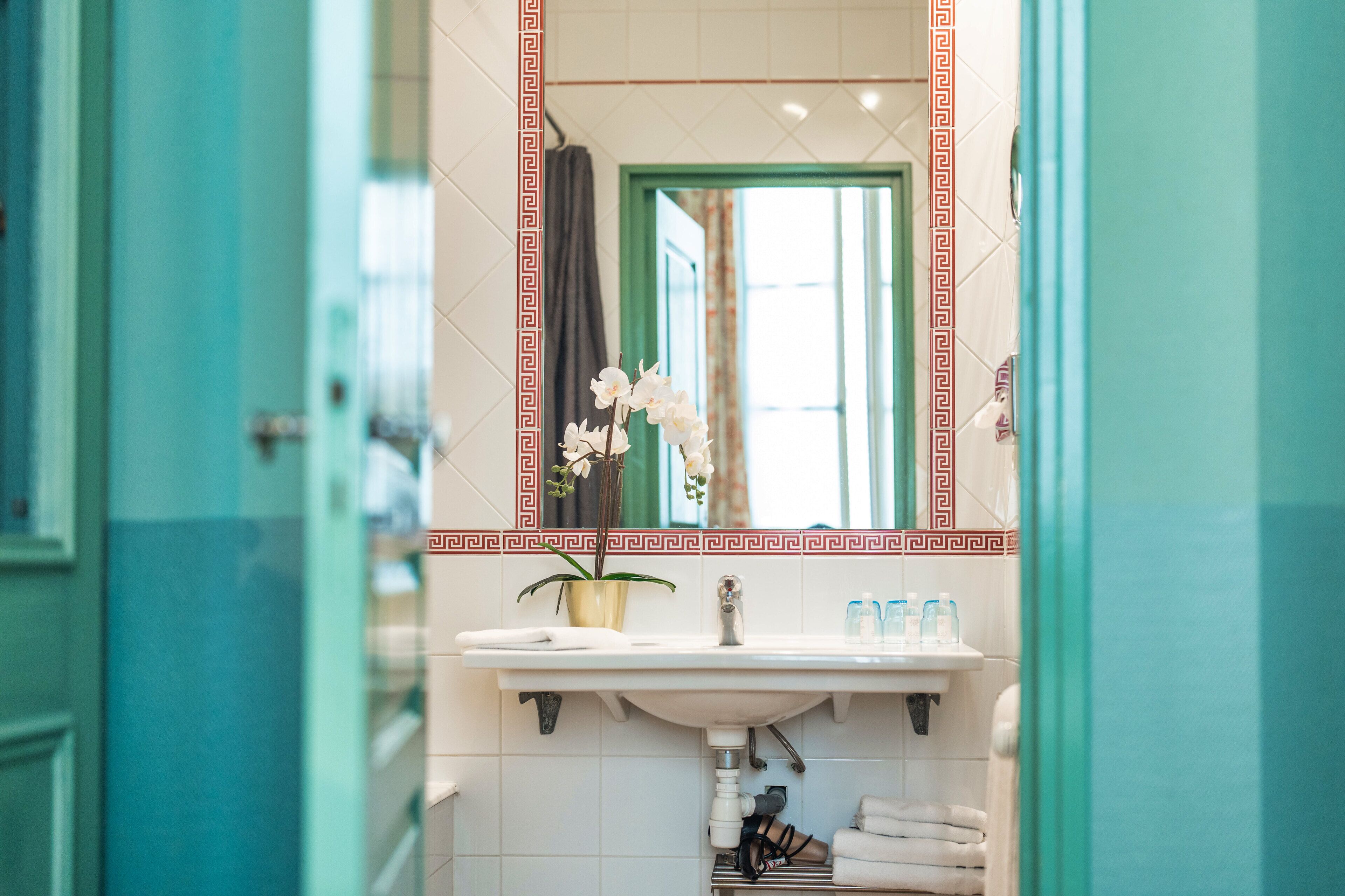 A bathroom with a sink, mirror, and potted orchid.