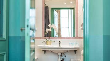 A bathroom with a sink, mirror, and potted orchid.