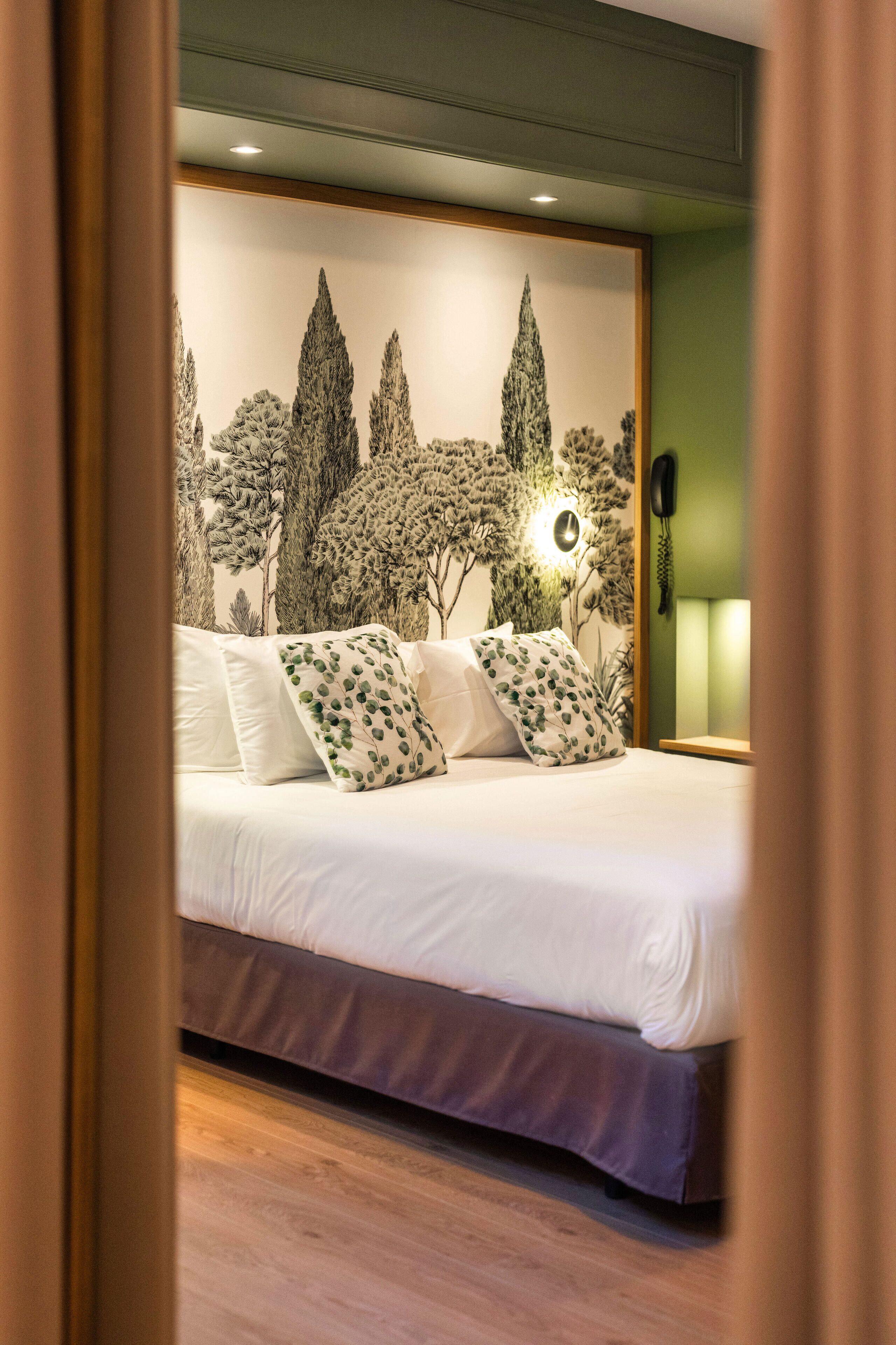 Une chambre à coucher avec un lit, des oreillers, un téléphone fixé au mur et une lampe fixée au mur.