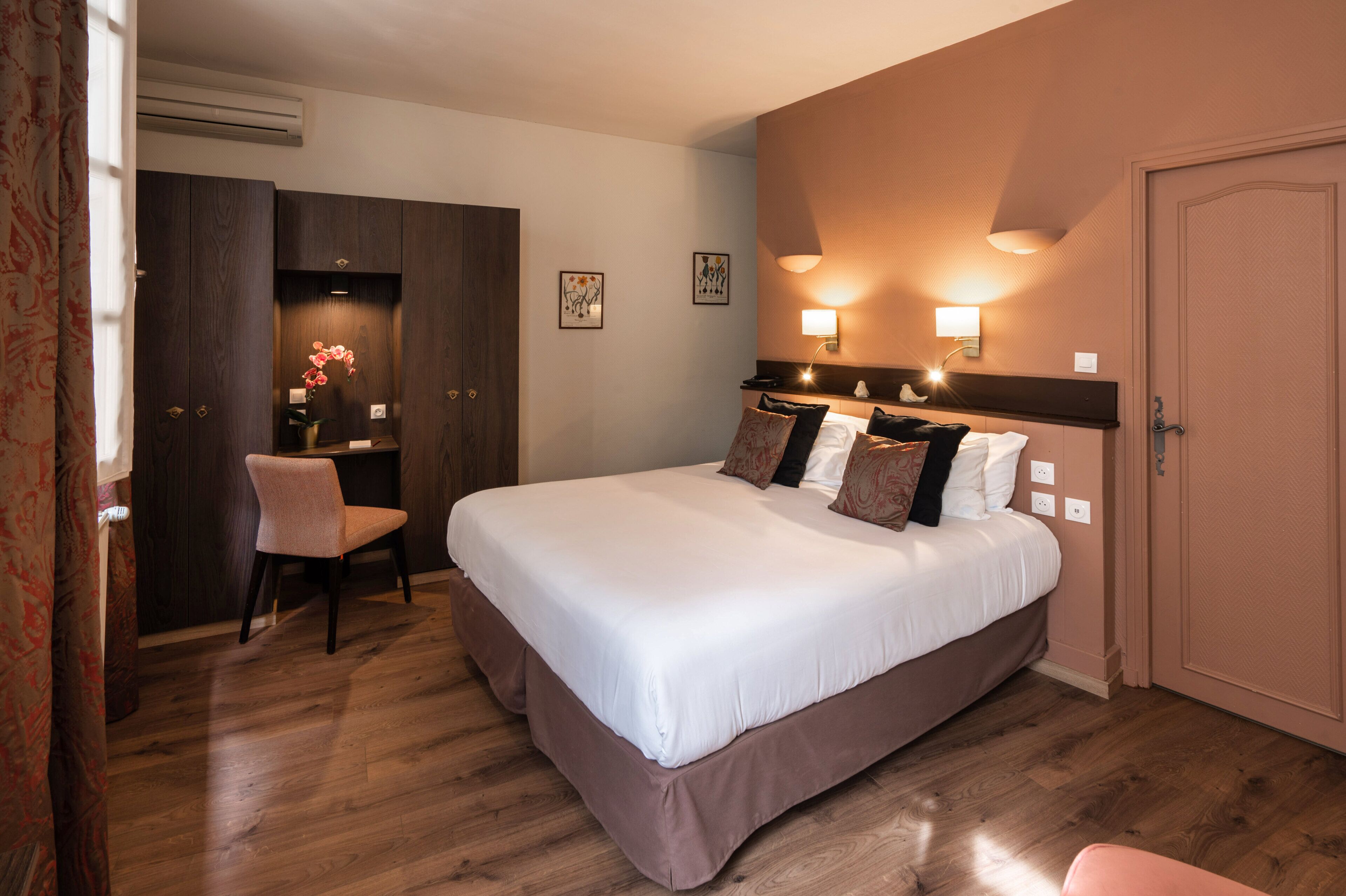 A hotel room with a large bed, a desk, and a chair.