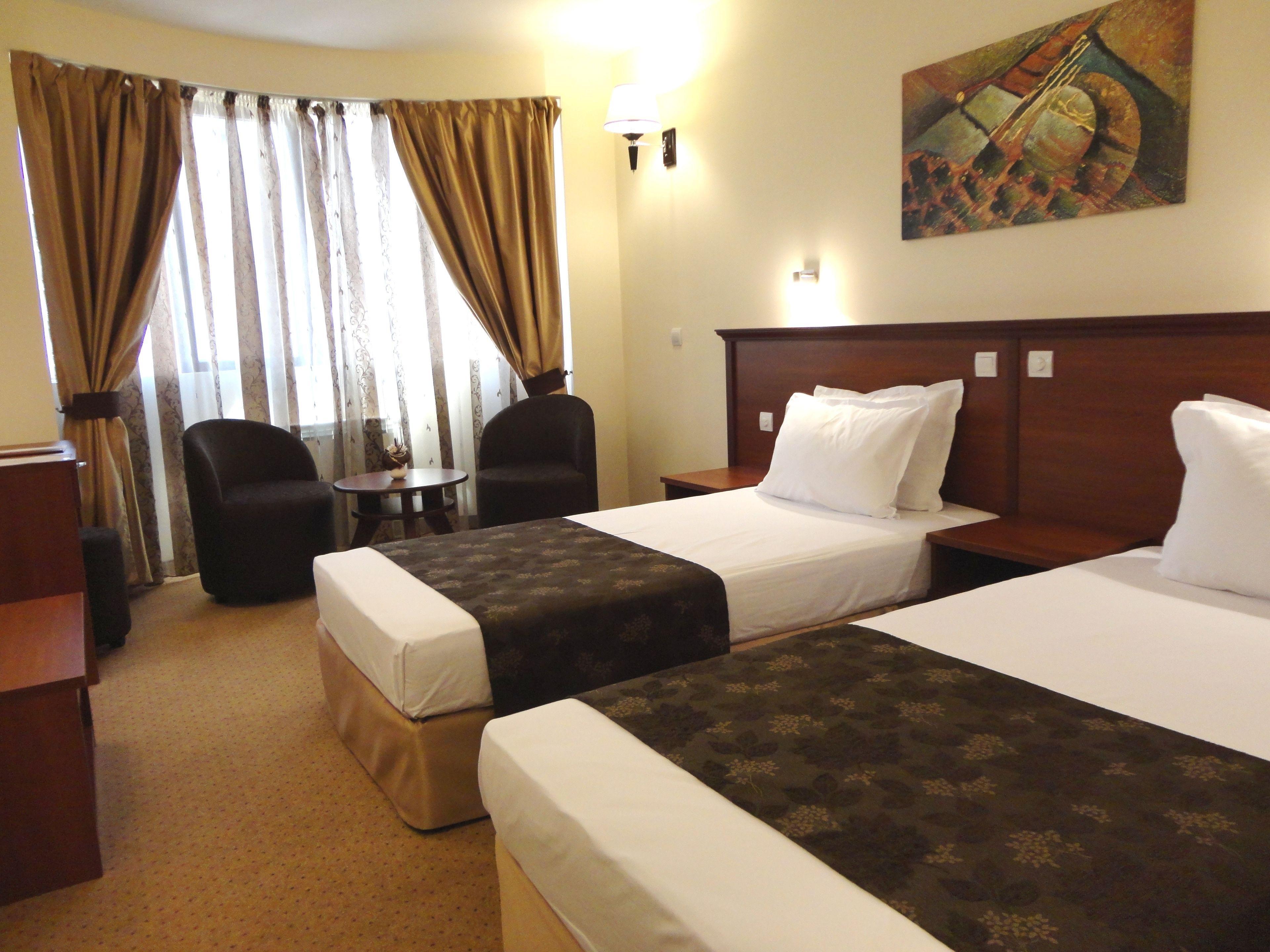 A hotel room with two beds, a desk, a chair, and a small table.