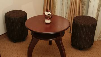 Una mesa redonda de madera con un jarrón de flores secas, acompañada de dos taburetes redondos con superficie texturizada.