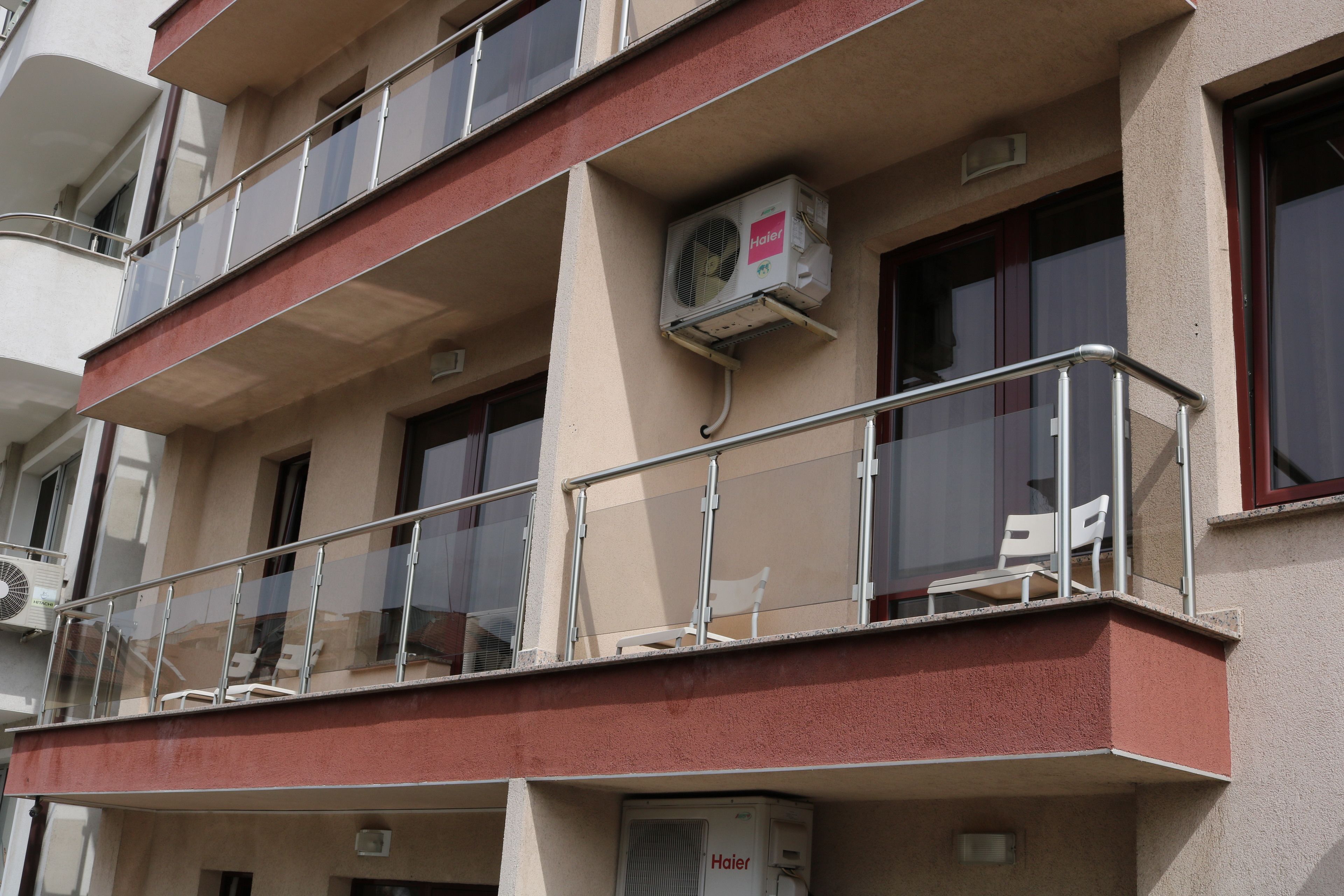 A multi-story building with balconies, air conditioning units, and a red exterior.