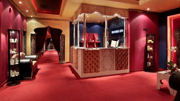A luxurious spa area with a red carpet, a reception desk, and a mirror cabinet. - Hotel Favorit (Sofia)